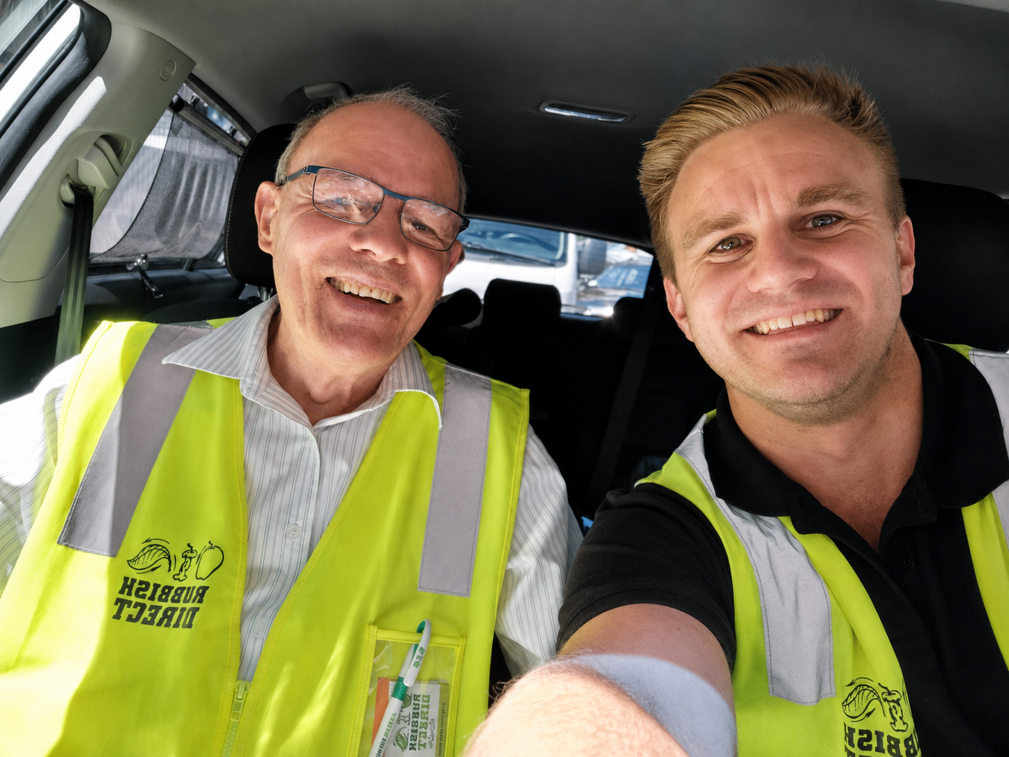 Two Smiling Men in High visibility Vests Inside a Vehicle Taking a Selfie on the Job Site