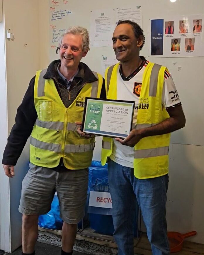 Celebrating years of excellence edward narayan at rubbish directjpg | Rubbish Direct Two Men in High visibility Vests Smile As One Holds a Framed Certificate of Appreciation Indoors with a Recycling Bin in the Background