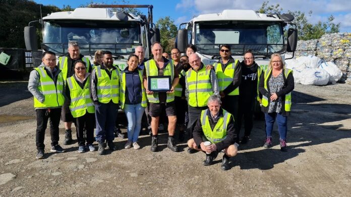 Shayne yearsjpg | Rubbish Direct Group of Workers in High visibility Vests Posing with a Framed Certificate in Front of Two Large Trucks Outdoors